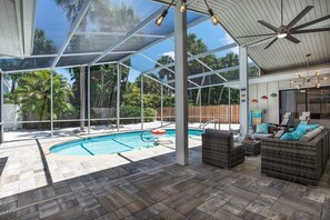 A covered outdoor area with a pool, wicker furniture, and a ceiling fan. - Sunkissed Pool Home, Fully Renovated, Pet Friendly (Siesta Key)