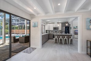 A modern kitchen with a central island, bar stools, and a view of a pool area. - Sunkissed Pool Home, Fully Renovated, Pet Friendly (Siesta Key)