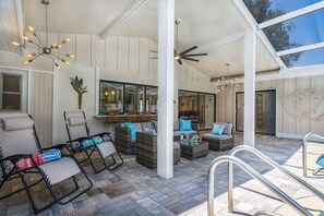 A covered outdoor seating area with wicker furniture and a ceiling fan.
