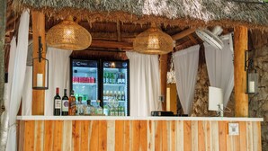 A bar area with wooden paneling, a thatched roof, and a refrigerator stocked with beverages. - Terasu Riviera Maya Hotel & Spa Luxury Edition, en Xcaret (Playa del Carmen)