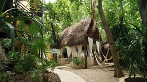 A thatched-roof structure surrounded by lush greenery and a curved pathway. - Terasu Riviera Maya Hotel & Spa Luxury Edition, en Xcaret (Playa del Carmen)