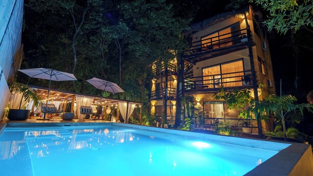 A poolside area with a large pool, outdoor seating, and a multi-story building with balconies. - Terasu Riviera Maya Hotel & Spa Luxury Edition, en Xcaret (Playa del Carmen)
