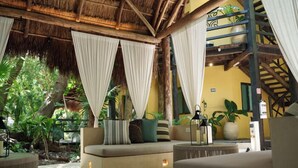 A room with a thatched roof, a staircase, and a seating area with cushions. - Terasu Riviera Maya Hotel & Spa Luxury Edition, en Xcaret (Playa del Carmen)