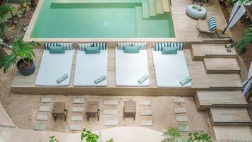 A rooftop pool area with multiple lounge chairs and a small seating area.