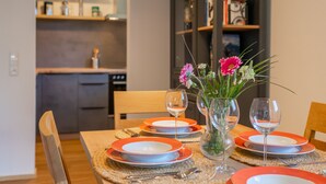A dining table set with orange plates, clear glassware, and a vase with flowers. - Small, charming, centrally located and yet quiet (Bad Hofgastein)