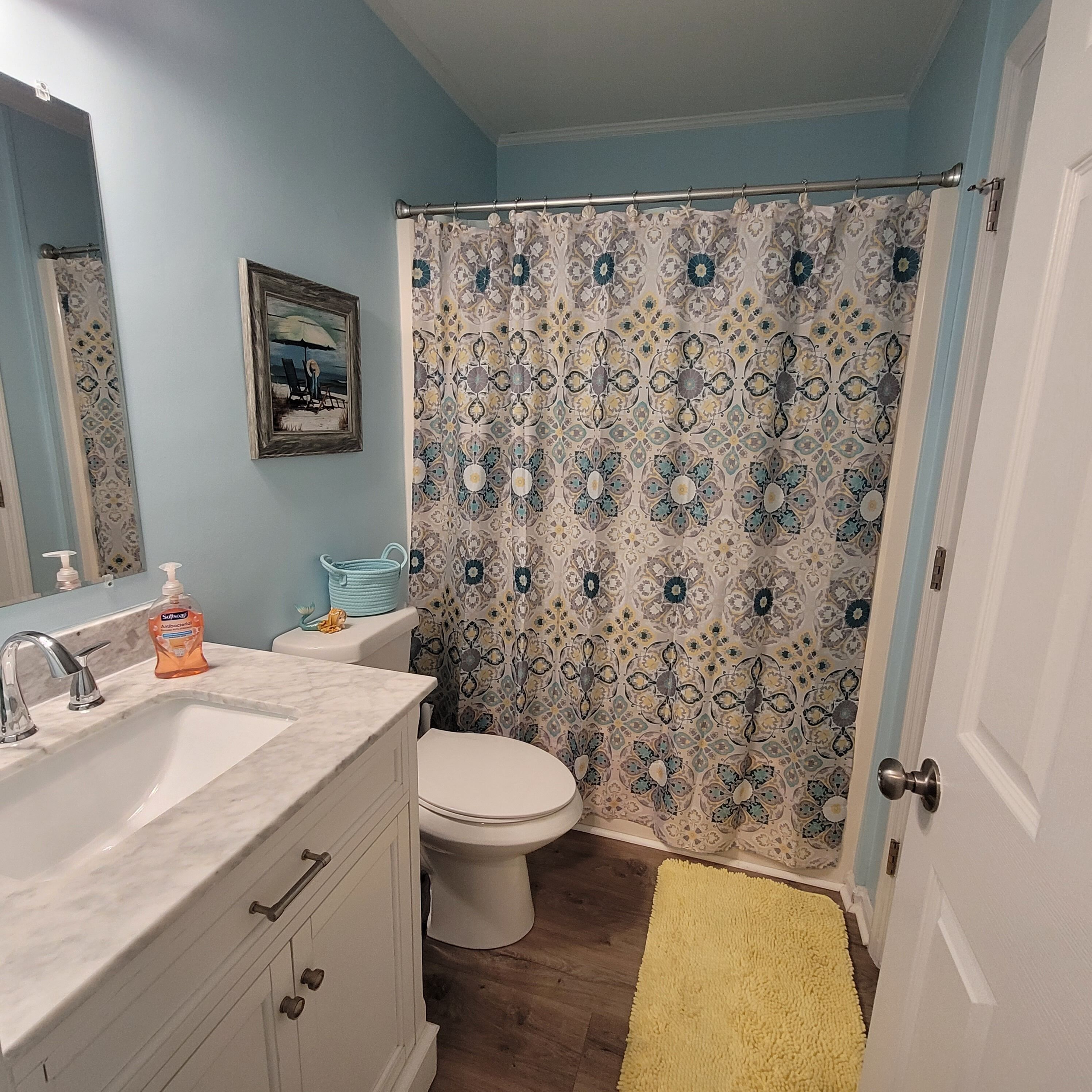 Un baño con lavamanos, inodoro y cortina de ducha.
