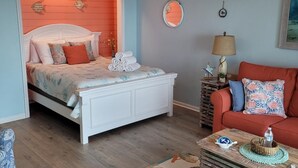 Un dormitorio con una cama, un sofá rojo, una mesa de centro y un ventilador de techo.