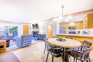 A modern kitchen with a central island, a dining area with a round table, and a living space with a fireplace.