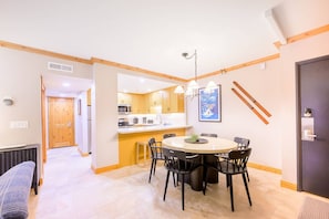 A modern kitchen with wooden cabinets, a central island, and a dining area with a round table and chairs.