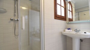 Une salle de bain moderne avec une douche à parois de verre, un lavabo blanc et un miroir avec un cadre en bois.