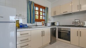 Une cuisine moderne avec des meubles blancs, un lave-vaisselle, un four et un four à micro-ondes.