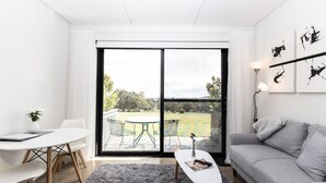 Ein modernes Wohnzimmer mit einem großen Schiebeglasfenster, das auf eine Terrasse im Freien führt.