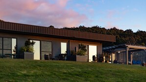 Ein modernes Haus mit flachem Dach, großen Fenstern und einem überdachten Sitzbereich im Freien.