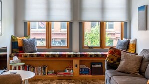 Un rincón acogedor para leer con un banco empotrado, una mesita y una estantería llena de libros.