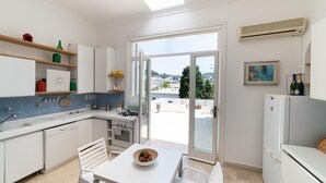 A modern kitchen with a view of the city, a dining area with a table and chairs, and a refrigerator. - Villa Birago in Capri (Capri)