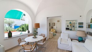 A spacious living area with a round table and chairs, a white sofa, and a glass cabinet with decorative items. - Villa Birago in Capri (Capri)