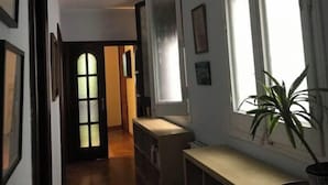 Ein Flur mit einer Holztür, einer Bank und einem Blumentopf in der Nähe eines Fensters.