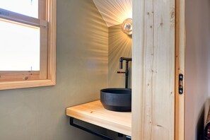 A bathroom with a wooden vanity, a black basin, and a wall-mounted light fixture. - O Lagar do Avô, a Home in Madeira (São Jorge)