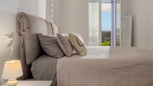A bedroom with a bed, pillows, a bedside lamp, and a view of the outdoors through a window. - Villa Natalka with garden in Valledoria (Valledoria)