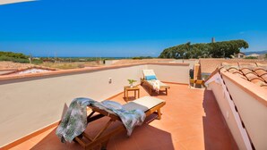 A rooftop terrace with a clear view of the sea, a lounge chair, a small table with a plant, and a tiled floor. - Villa Natalka with garden in Valledoria (Valledoria)