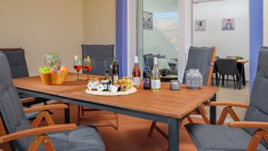 A dining area with a wooden table set for a meal, surrounded by grey upholstered chairs. - Villa Natalka with garden in Valledoria (Valledoria)