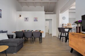 Ein modernes Wohnzimmer mit grauem Sofa, einem Holztisch und einem Essbereich mit Holztisch und vier Stühlen.