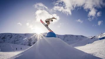 Un skieur effectuant un saut au-dessus d’une rampe de neige, avec un ciel dégagé en arrière-plan.