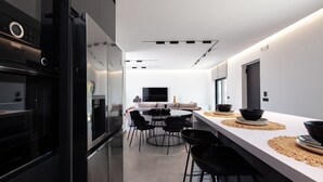 A modern kitchen with a central island, black chairs, and a dining table. - Horizon Villa Oasis, Walk to Platanias Beach! (Chania)