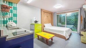 A compact hotel room with a kitchenette, a bed, a small table, and a sliding glass door to a balcony. - Gapyeong Namueuikkum Pension (Gapyeong)