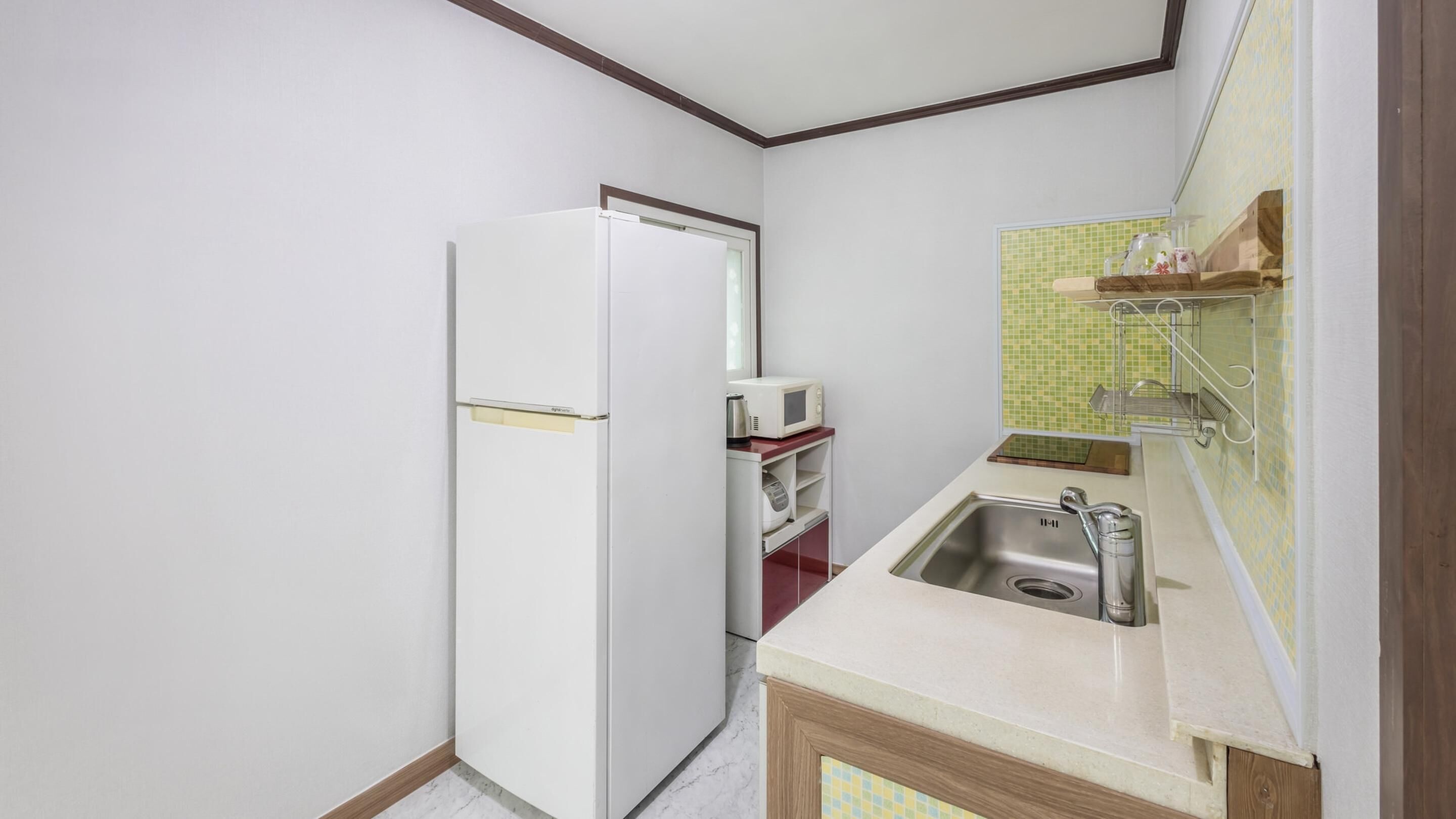 A compact kitchen with a refrigerator, a microwave, and a sink.