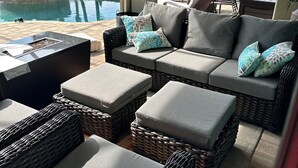 A sunlit outdoor seating area with wicker furniture, a pool, and a view of a marina. - Eight Palms/ Punta Gorda Waterfront Paradise Escape (Punta Gorda)