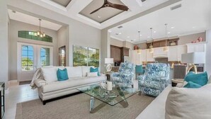 A spacious living room with a glass coffee table, a white sofa with blue cushions, and patterned armchairs. - Eight Palms/ Punta Gorda Waterfront Paradise Escape (Punta Gorda)