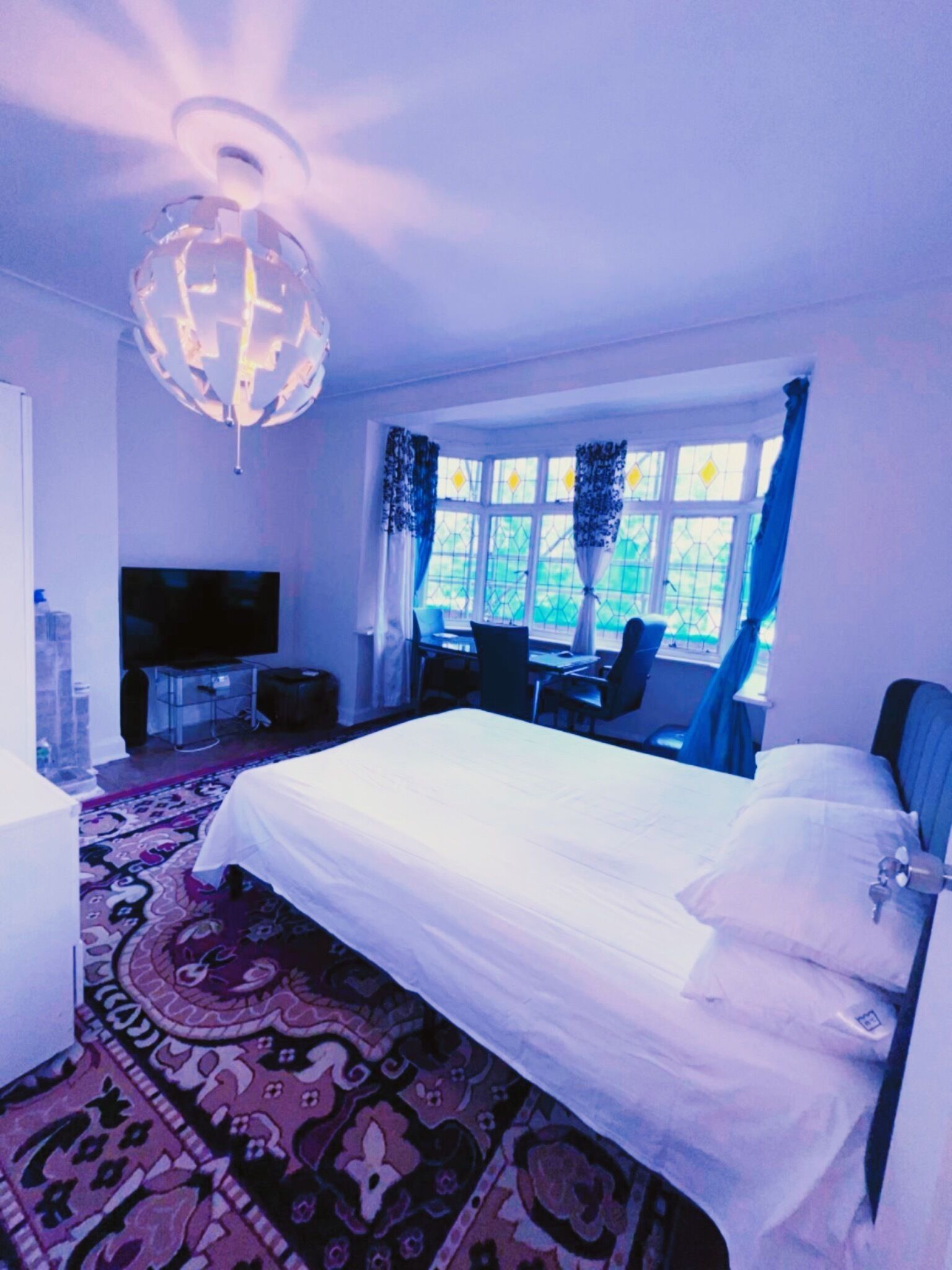 Une chambre d’hôtel équipée d’un lit, d’un bureau, d’une chaise, d’une télévision et d’une fenêtre avec des rideaux.