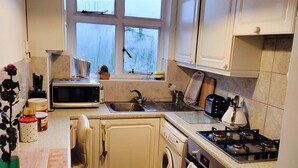 Kompakti keittiö, jossa on pesukone, mikroaaltouuni, pesuallas ja liesi.