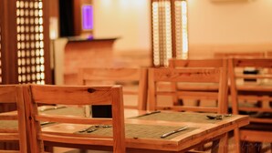 L’intérieur d’un restaurant avec des tables et des chaises en bois, un comptoir et un luminaire décoratif.