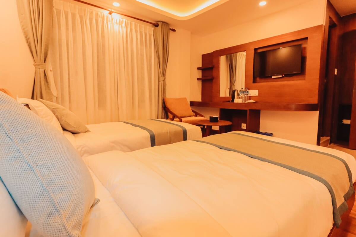Een hotelkamer met twee bedden, een televisie, een stoel en een tafeltje.