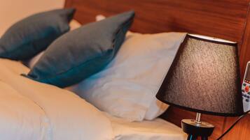 A bed with white and blue bedding, a black lamp, and a wooden headboard.