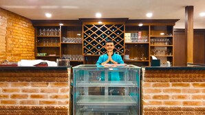 Un espace bar avec un barman, des étagères remplies de verres et un présentoir.