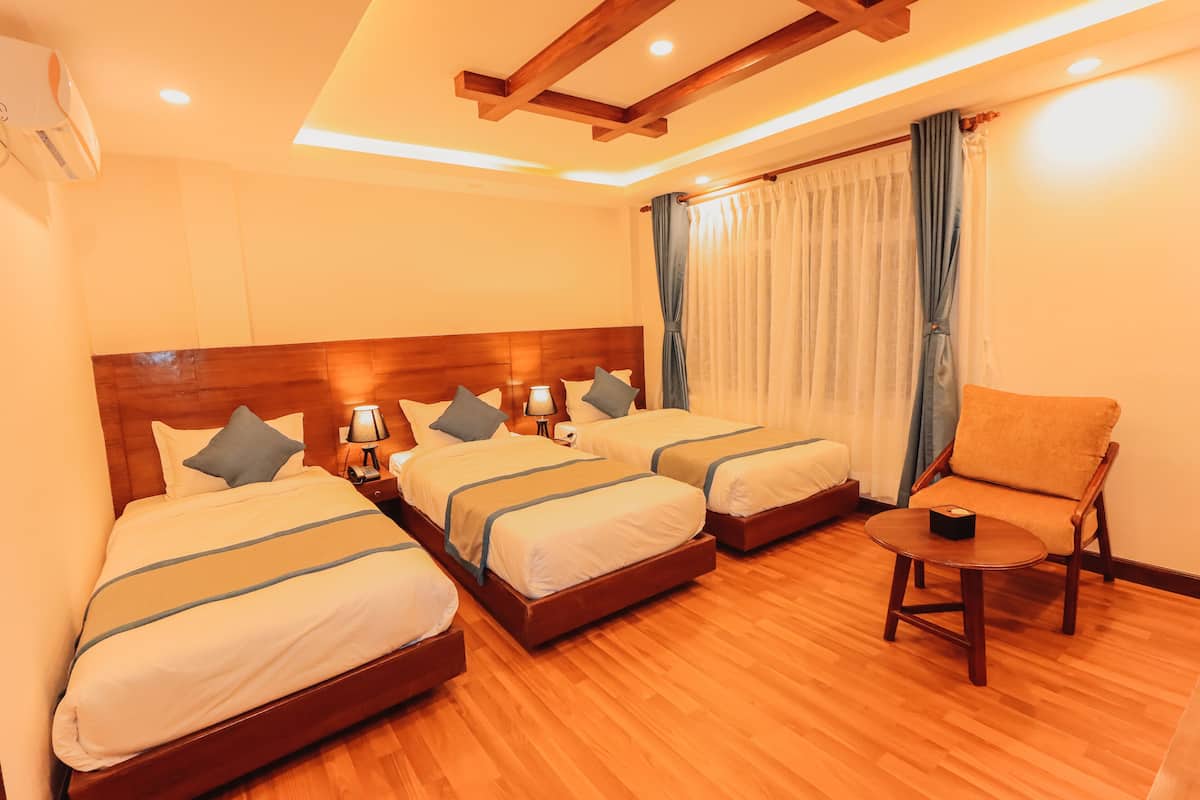 Een hotelkamer met twee bedden, een houten hoofdeinde, een klein rond tafeltje en een stoel.