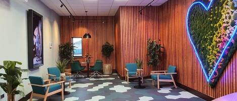 A modern waiting area with a heart-shaped floral wall, comfortable seating, and a projector screen.