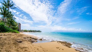 A beach with clear skies, palm trees, and a building in the background. - Direct oceanfront resort offers great ocean views (Lahaina)