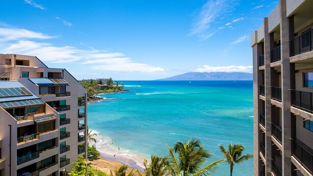 A high-rise hotel with multiple balconies overlooking a beach and ocean. - Direct oceanfront resort offers great ocean views (Lahaina)