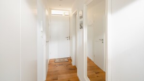 Un couloir étroit avec un plancher en bois et des murs blancs.