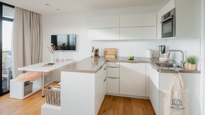 Une cuisine moderne avec des meubles blancs, un four encastré et un grand îlot central doté d’un évier.