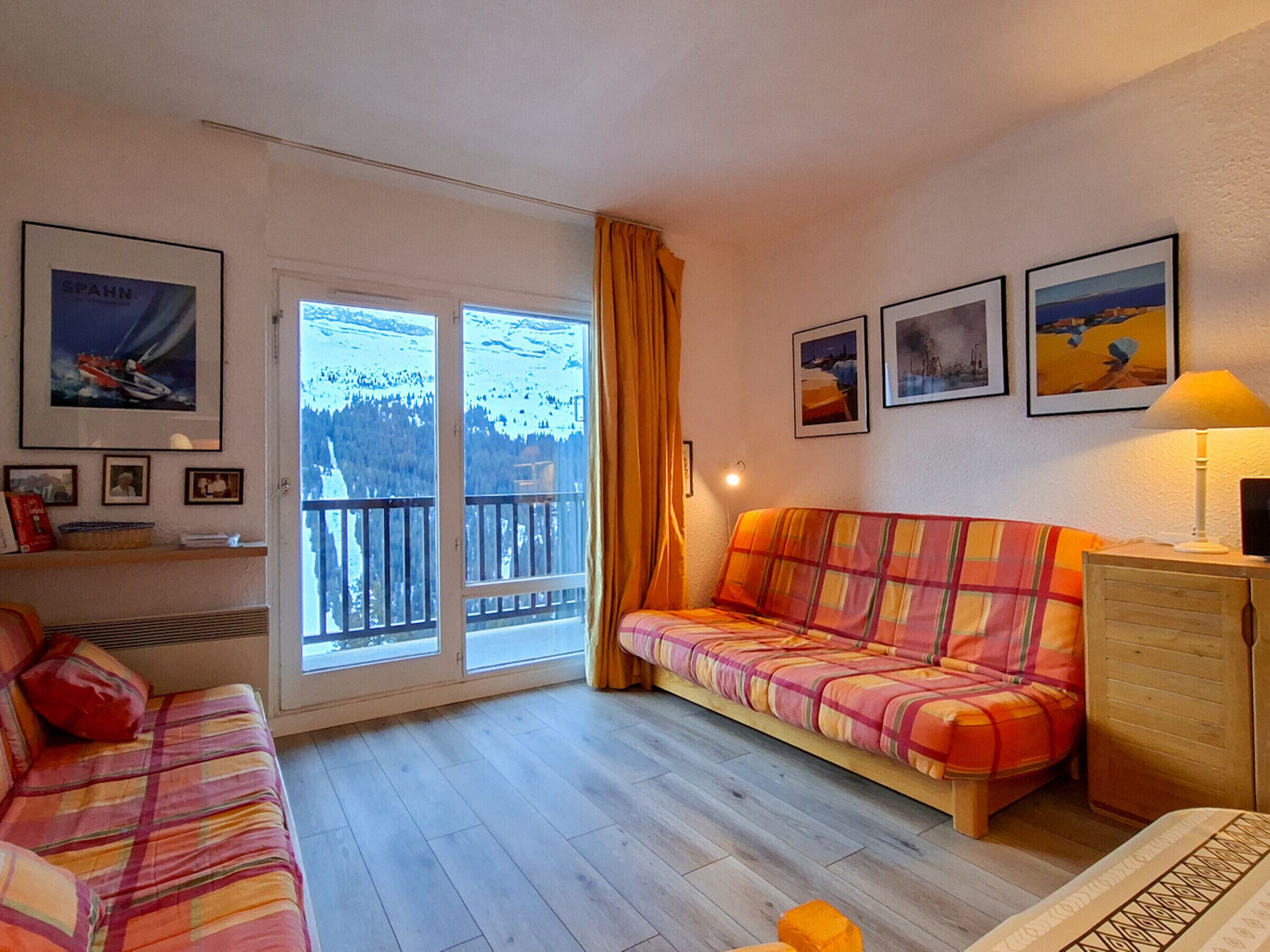 A cozy living room with a sofa, a wooden cabinet, and a window with a view of a snowy landscape.