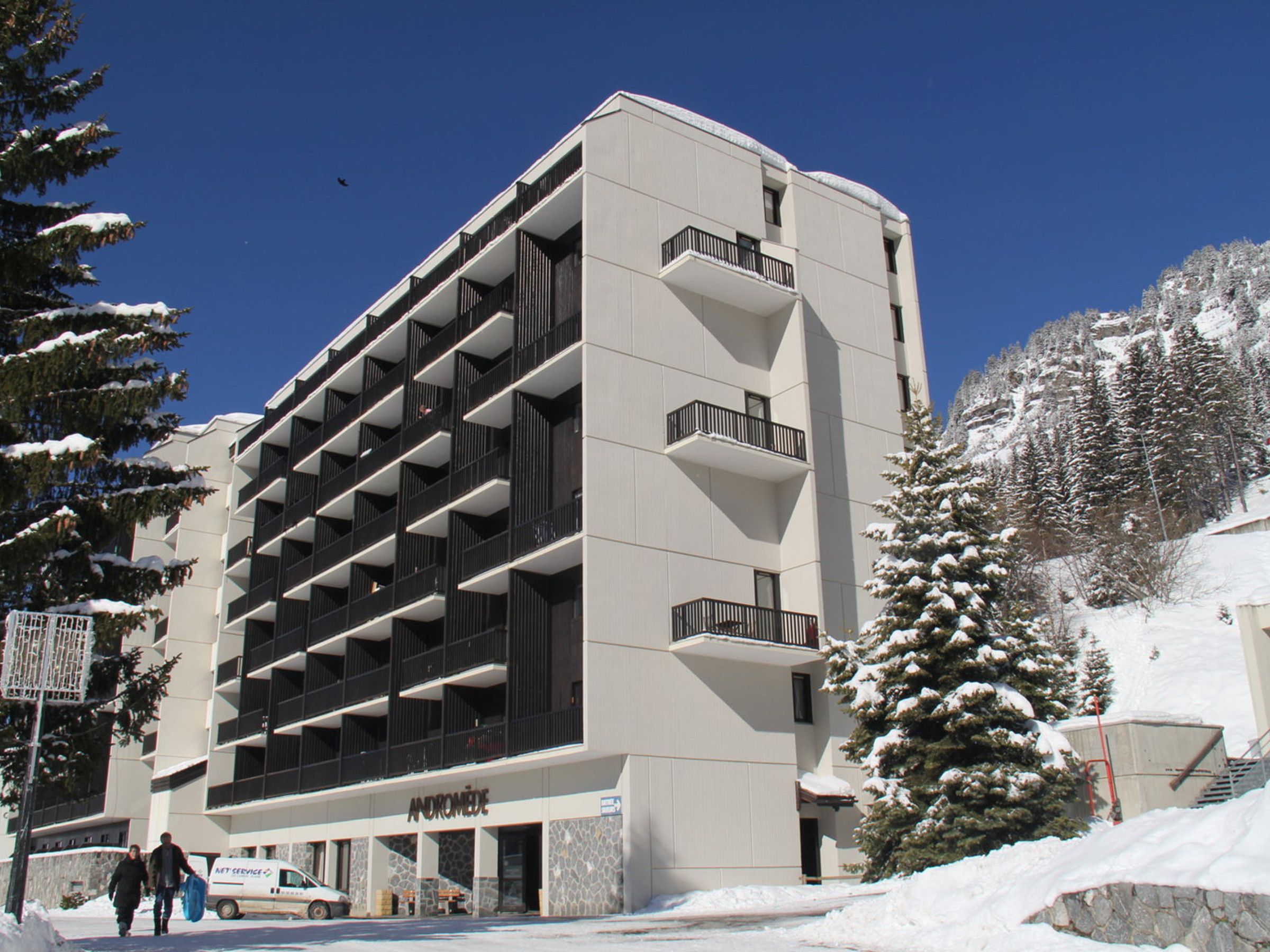 A multi-story building with a modern architectural design, featuring a series of balconies and a stone facade.