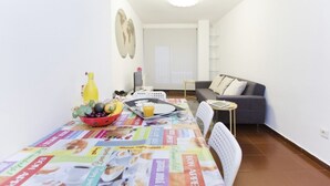 Et lille, lyst rum med et spisebord dækket til to personer, en sofa og et lille sofabord.