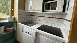 A compact kitchen with a dishwasher, a sink, and a microwave.