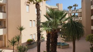 Un patio con palmeras y un edificio con balcones.