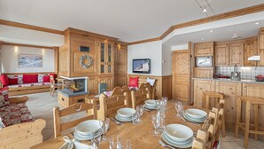 Uma sala de jantar com uma mesa de madeira posta para seis pessoas, rodeada por cadeiras de madeira.